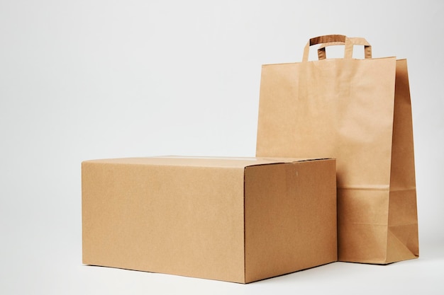 Karton i papierowa torba na białym tle na białym tle z miejsca na kopię Koncepcja usługi dostawy i wysyłki Papierowa torba na zakupy i opakowanie paczek zbliżenie