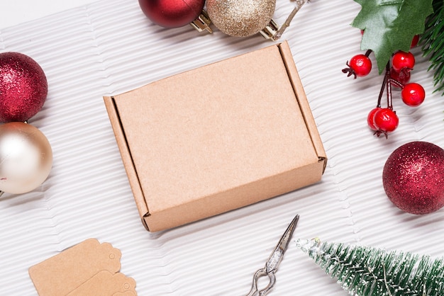 Kartonowe pudełko na drewnianym biurku ozdobione świąteczną ozdobą
