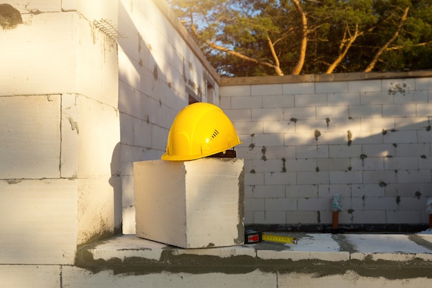 Kask budowlany i taśma miernicza na oknie budowanego domu z bloków z betonu porowatego. Przepływ pracy, architektura i inżynieria, budownictwo. Bezpieczeństwo pracy i narzędzia.