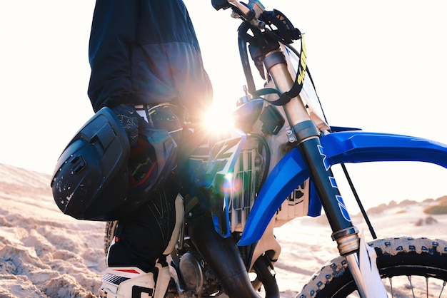 Kask motocyklowy i mężczyzna na pustyni do podróży przygodowych i flary obiektywu Dłoń motocykla i zbliżenie jeźdźca na łonie natury dla wolności, treningu sportowego i jazdy po piasku i podróży terenowej