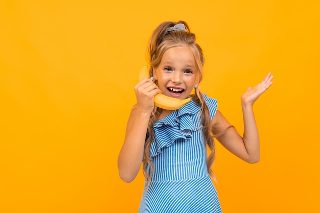 Kaukaska blond dziewczyna trzyma banana na pomarańcze