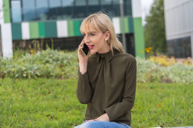 Kaukaska blondynka przedsiębiorca w parku biznesowym podczas rozmowy przez telefon