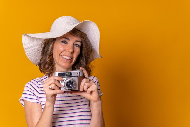 Kaukaska Dziewczyna W Koncepcji Turystycznej Z Aparatem Fotograficznym W Dłoni I Ciesząca Się Letnimi Wakacjami Na żółtym Tle