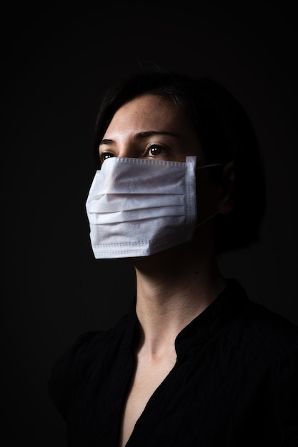Kaukaska kobieta jest ubranym białą maskę medyczną dla ochrony przed koronawirusem