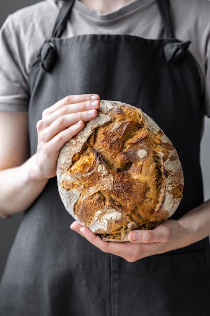 Kaukaska kobieta trzymająca świeży chleb z pieca piecze domowy chleb