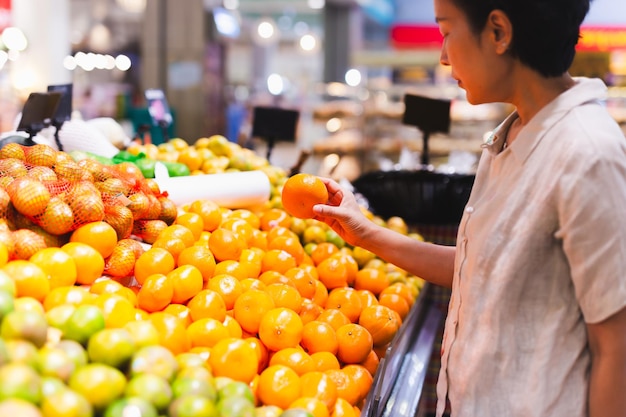 Kaukaska konsumentka w sklepie spożywczym wybierająca pomarańczowe soczyste cytrusy
