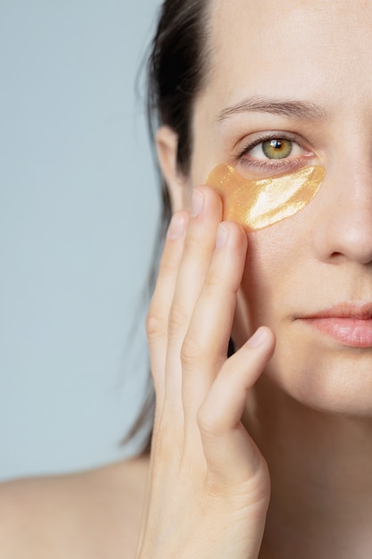Kaukaska lub europejska kobieta ze złotymi plamami pod oczami dba o nawilżenie skóry