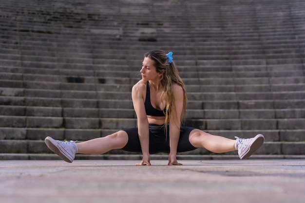 Kaukaska młoda kobieta uprawiająca fitness w parku miejskim, robiąca szpagat i wznosząca się w powietrze