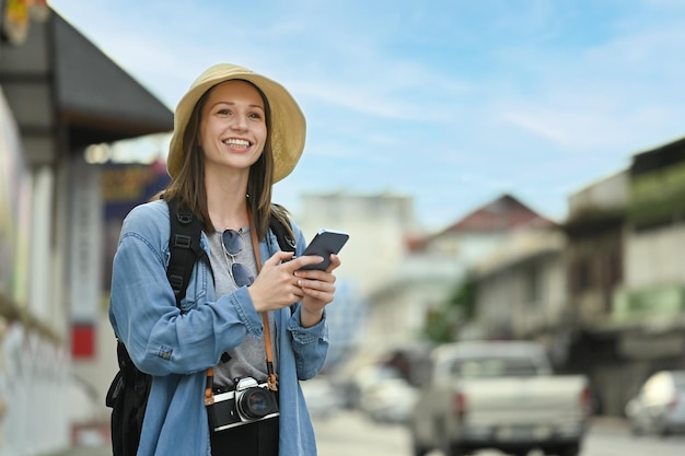 Kaukaska podróżniczka korzystająca ze smartfona i czekająca na taksówkę do transportu koncepcji turystyki i transportu