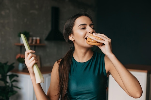 Kaukaska wysportowana kobieta tracąca siłę woli i gryząca cheeseburgera piękny portret dieta ve