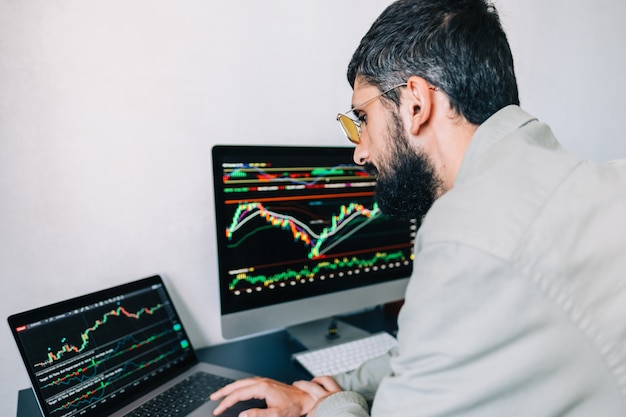 Zdjęcie kaukaski biznesmen handlujący online, korzystający z technologii komputerowej, patrzący na handel giełdowy i analizujący