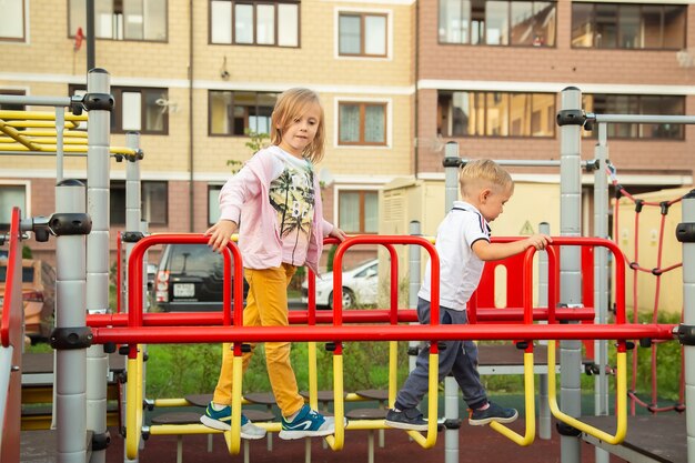 Kaukaski chłopiec i dziewczynka wspinają się na plac zabaw na tle domów