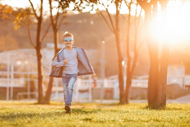Kaukaski chłopiec w okularach spaceruje po jesiennej przestrzeni kopii parku
