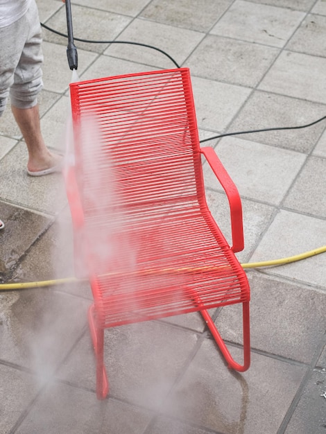 Kaukaski facet w szarych dresach myje krzesło z czerwonego drutu