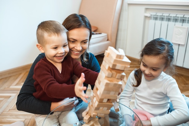 Kaukaski Matka I Jej Syn I Mała Dziewczynka Gra Jenga Na Szklanym Stole Uśmiechając Się Razem