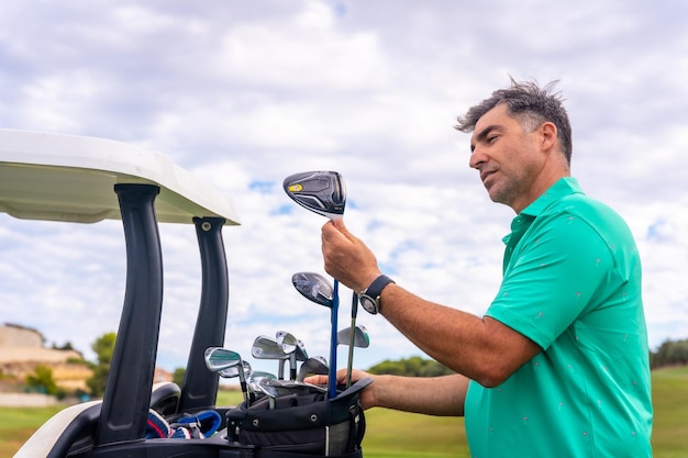 Kaukaski Mężczyzna Grający W Golfa W Klubie Golfowym Sprawdzający Kije Golfowe W Buggy W Pochmurny Dzień