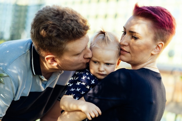 Kaukaski mężczyzna i kobieta rodzice małej dziewczynki całują swoją córeczkę