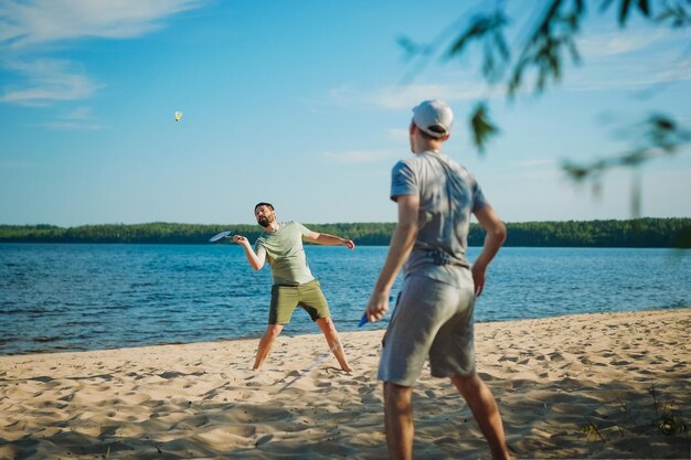 Kaukaski mężczyzna i syn nastolatka grają w badmintona nad jeziorem Koncepcja rodziców i nastolatków Obraz z selektywnym skupieniem