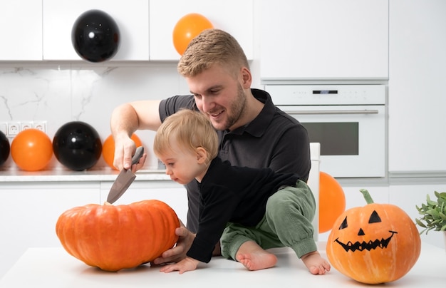 Kaukaski mężczyzna kroi dynię w kuchni Ojciec spędza czas z dzieckiem Szczęśliwego dnia Halloween z rodziną