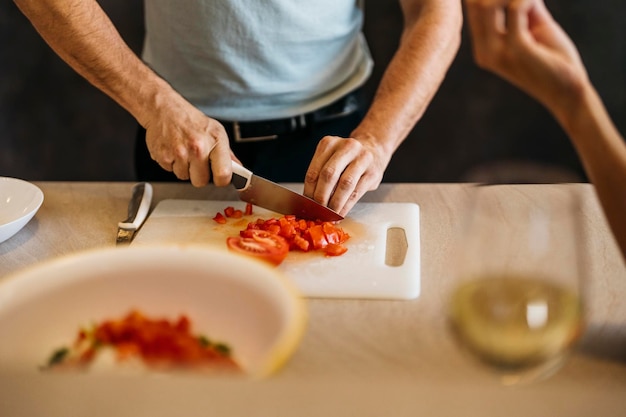 Kaukaski mężczyzna kroi pomidora na sałatkę na desce do krojenia w kuchni