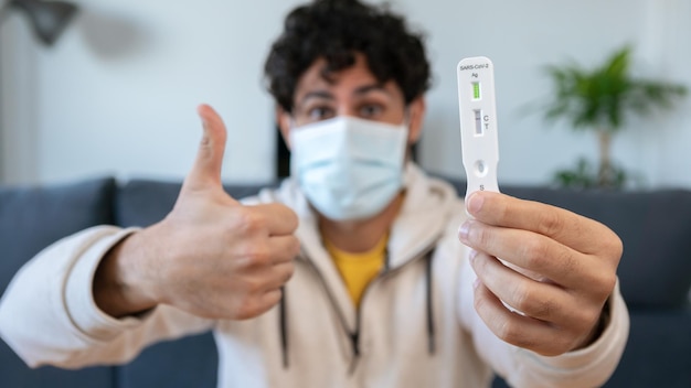 Kaukaski mężczyzna pokazujący kciuk w górę po wykonaniu szybkiego domowego urządzenia testowego na wirusa Covid19 z wynikiem ujemnym Kaseta antygenowa testu ekspresowego pcr na nowy wariant wirusa Omicron
