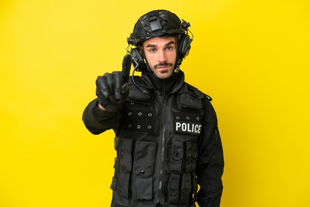 Kaukaski mężczyzna SWAT na żółtym tle pokazujący i unoszący palec
