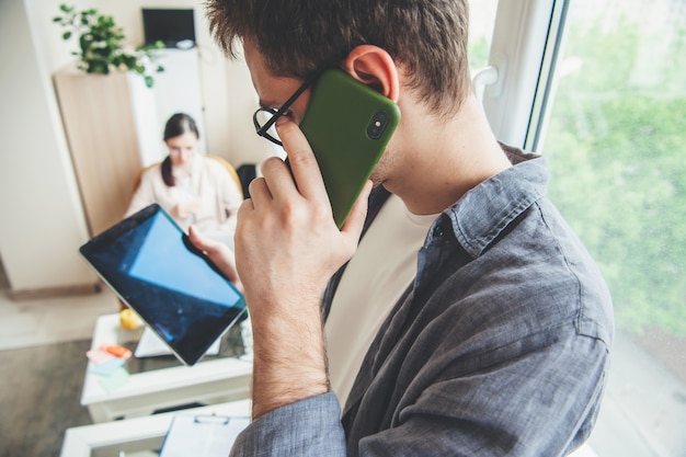 Kaukaski Mężczyzna W Okularach Patrzy Na Ekran Tabletu Podczas Rozmowy Telefonicznej