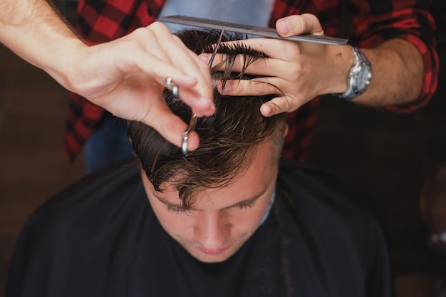 Kaukaski młody mężczyzna w Barbershop Fryzjer obcina włosy w hipsterskim stylu