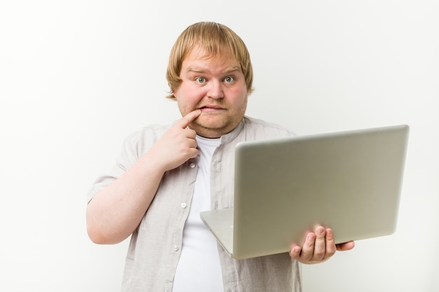 Kaukaski plus size mężczyzna trzyma laptop zrelaksowany, myśląc o czymś, patrząc na miejsce.