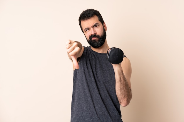 Kaukaski sport mężczyzna z brodą co podnoszenie ciężarów pokazano kciuk w dół dwiema rękami