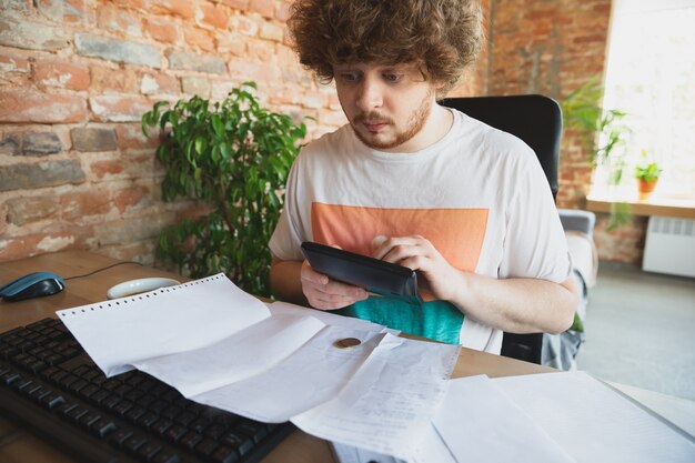 Kaukaski Zdenerwowany I Zrozpaczony Mężczyzna Robi Raporty Finansowe I Ekonomiczne, A Dochody Spadają Podczas Kwarantanny Koronawirusa, Problemy. Kryzys światowy. Obniżenie Dochodów, Brak Pieniędzy, Upadek Biznesu.