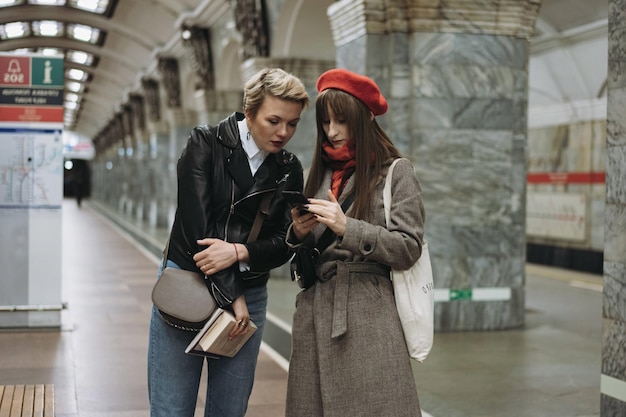 Kaukaskie dziewczyny stojące na peronie stacji metra i czytające coś na peronie