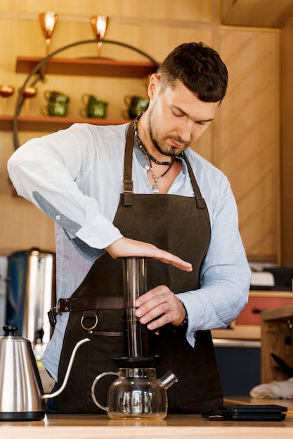 Kawa Aeropress: barista prasa do urządzenia, a krople kawy wylewają się przez aeropress do garnka