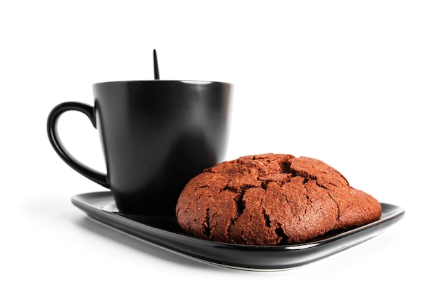Zdjęcie kawa americano w filiżance i spodeczku na białym tle na białym tle. gorąca kawa z pianką. kawa z czekoladowym ciasteczkiem. zdjęcie wysokiej jakości