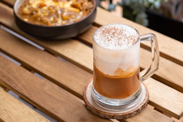 Kawa cappuccino w przezroczystej filiżance na drewnianym stole z