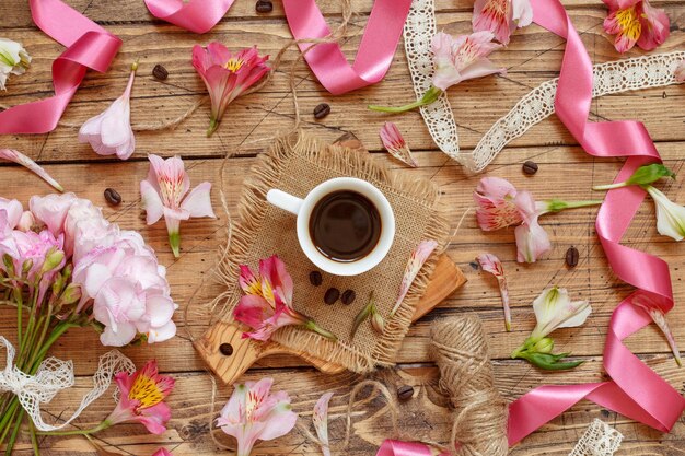 Kawa i różowe kwiaty na drewnianym stole z widokiem