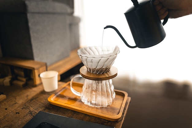 Zdjęcie kawa kroplowa, barista nalewający wodę na zmieloną kawę z filtrem, zaparzanie kawy