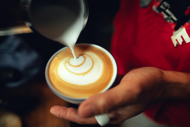 Kawa latteZbliż się do ręki nalewając kawę latte art.