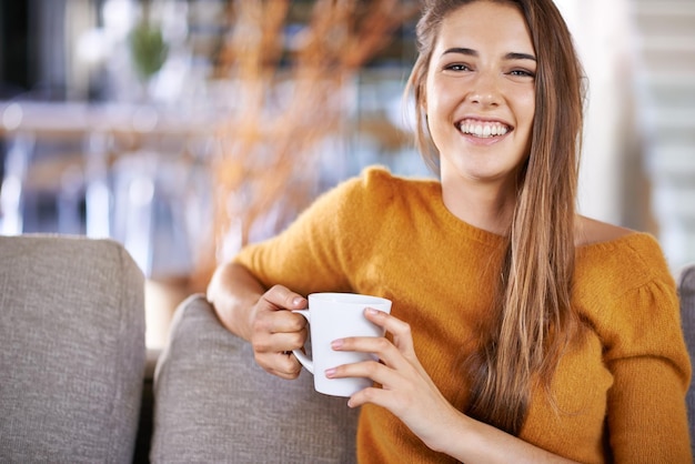Kawa mnie uszczęśliwia Przycięty obraz ładnej młodej kobiety pijącej kawę siedzącą na kanapie