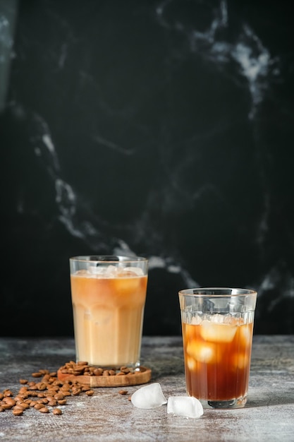 Kawa mrożona w wysokiej szklance z wylaną śmietaną, kostkami lodu i ziarnami na starym rustykalnym drewnianym stole