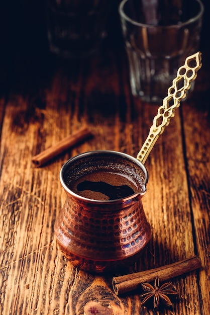 Kawa po turecku z cynamonem i anyżem. Parzona kawa w miedzianym cezve na drewnianej powierzchni
