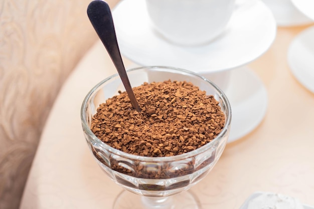 Kawa rozpuszczalna w szklanej misce na tle białych filiżanek kawy