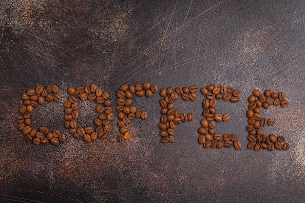 Zdjęcie kawa słowo wykonane z ziaren kawy, ciemne tło zardzewiałe, widok z góry, miejsce.