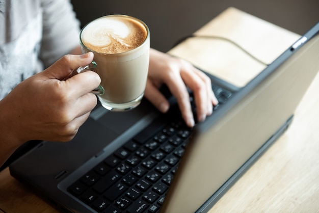 Kawa W Ręki Biurowej Dziewczynie Używa Laptop.