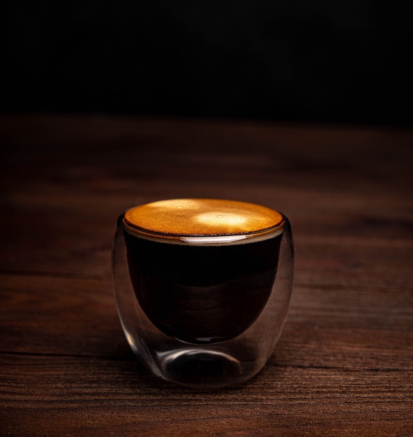 Kawa w szklanej filiżance na drewnianym stole