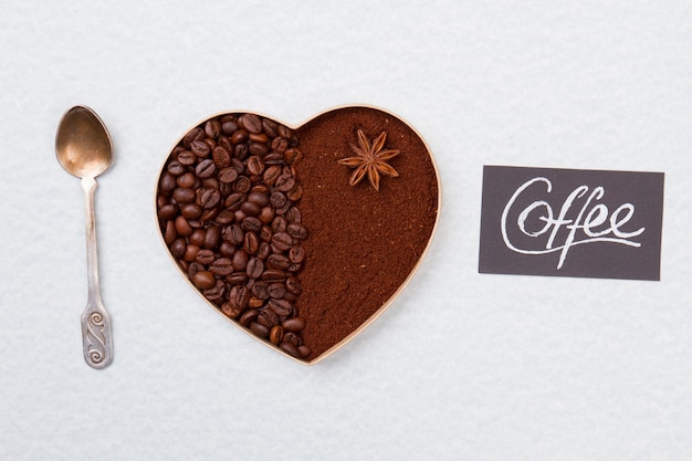 Kawa ziarnista i kawa rozpuszczalna w kształcie serca. Srebrna łyżeczka. Na białym tle na białej powierzchni