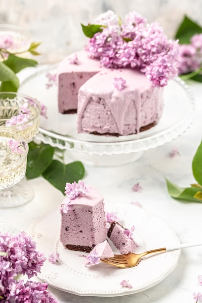 Kawałek ciasta musowego Pyszna deserowa tarta jagodowa ze świeżymi jagodami z bukietem fioletowych kwitnących bzów pionowe miejsce na tekst