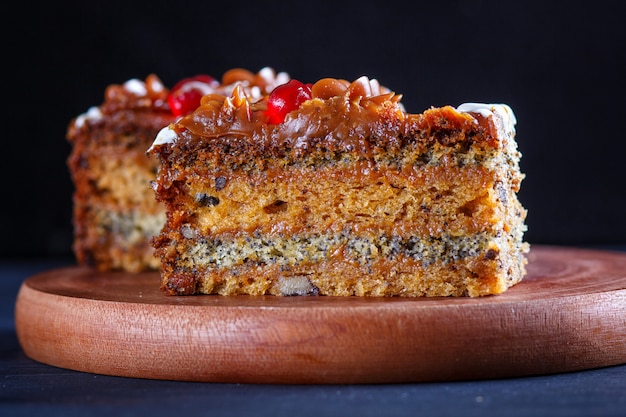 Kawałek Ciasta Z Kremem Karmelowym I Makiem Na Drewnianej Desce Kuchennej, Czarne Tło.