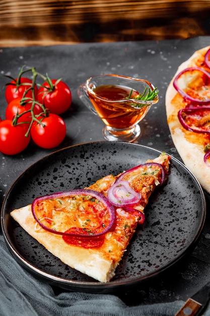 Kawałek klasycznej włoskiej pizzy pepperoni z cebulą na talerzu
