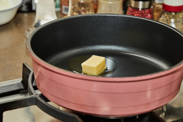 Kawałek masła topi się na patelni przed gotowaniem